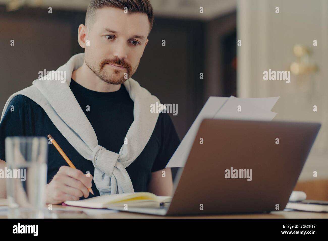 Uomo d'affari impegnato a utilizzare il computer portatile e a prendere appunti sul posto di lavoro Foto Stock