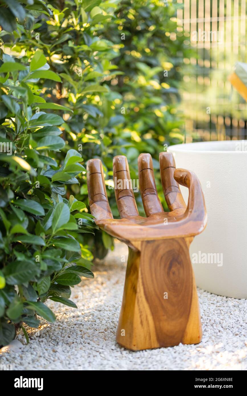 Poltrona in legno a forma di mano vicino alla siepe verde. Angolo  tranquillo e rilassante nel giardino Foto stock - Alamy