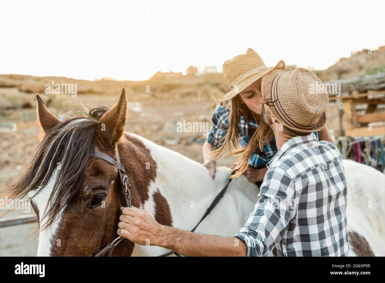 Felice coppia di contadini che baciano mentre cavalcano all'interno del ranch Foto Stock