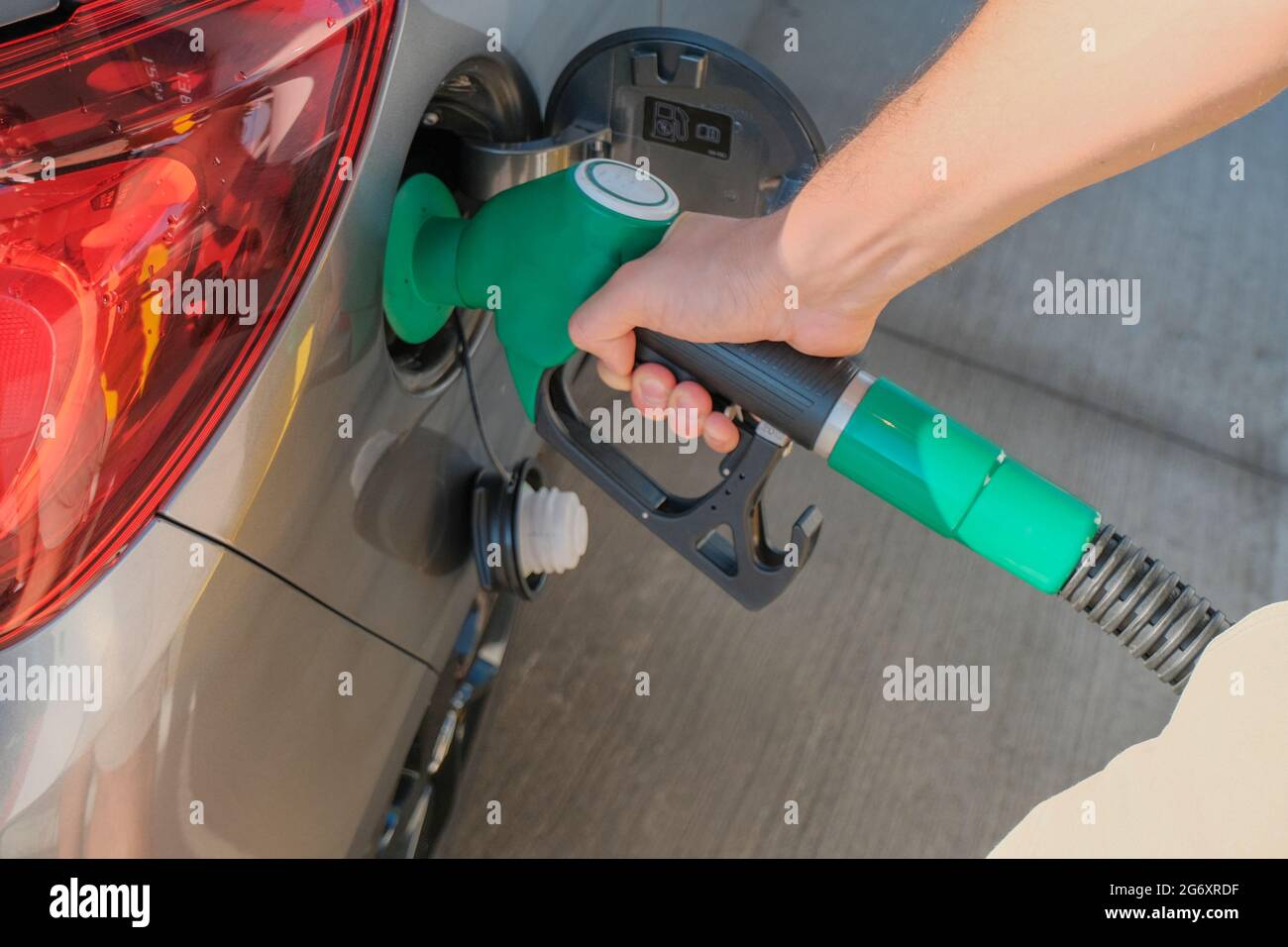 Mani dell'uomo che tengono la pompa del gas e riempiono l'auto di carburante da vicino. Industria energetica. Stazione di benzina business / mercato. Foto Stock