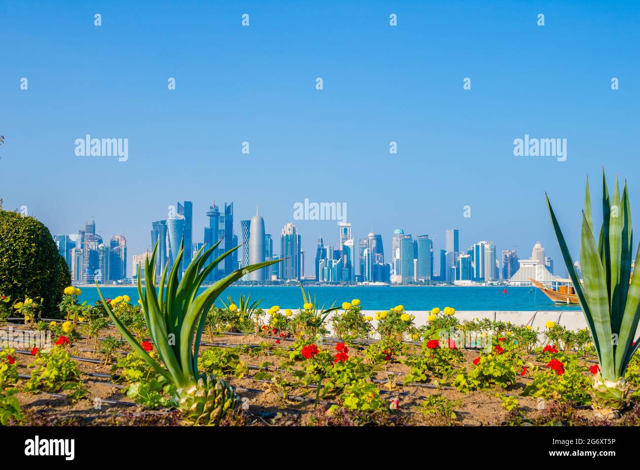 Incredibile skyline di Doha City in Qatar con un bel letto di fiori in primo piano. Questo breve è stato preso lungo la Corniche Foto Stock