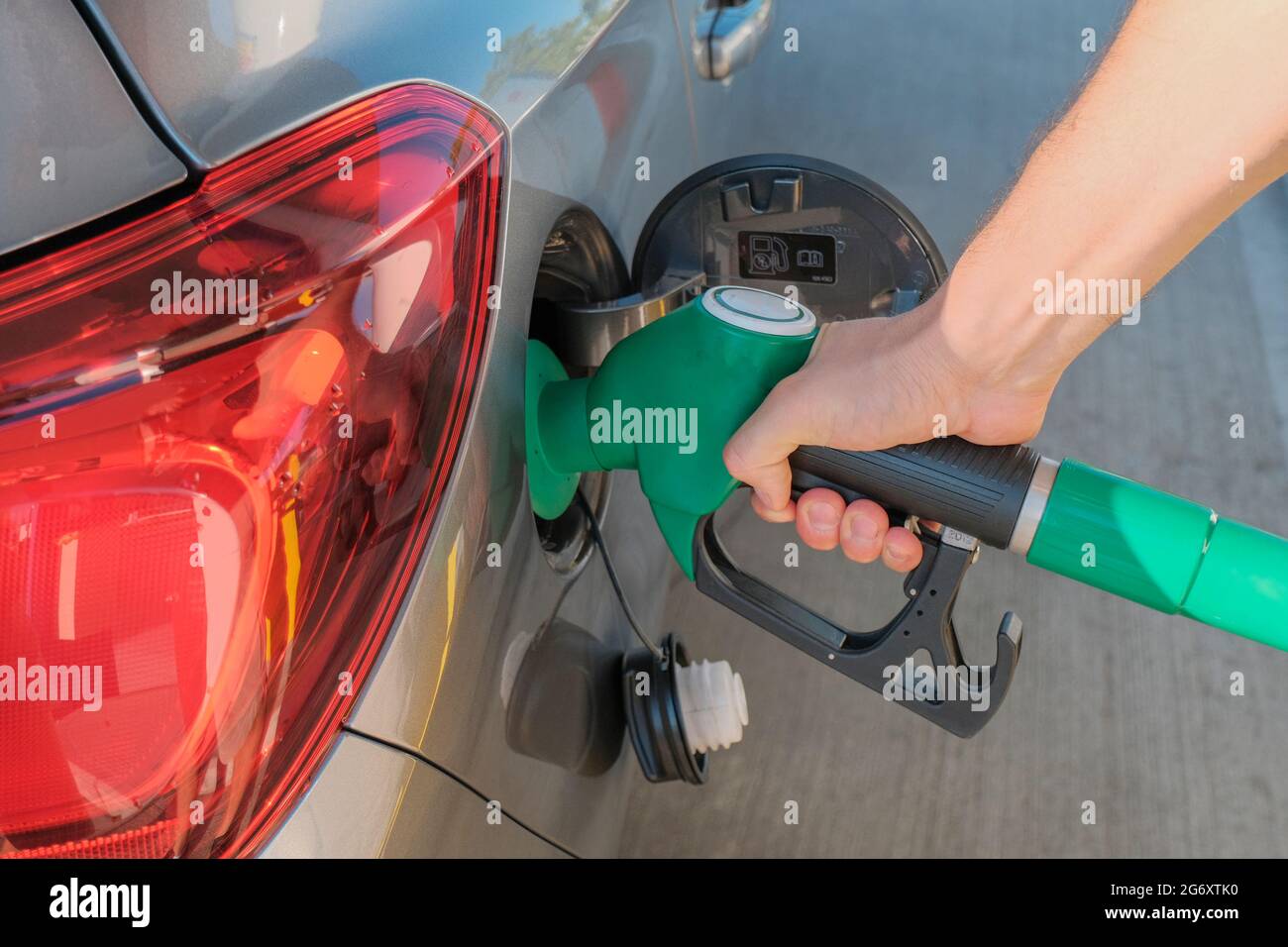 Le mani dell'uomo tengono la pompa di benzina, rifornendo la sua auto con carburante vicino attraverso le strade della città. Industria energetica. Stazione di benzina business / mercato Foto Stock