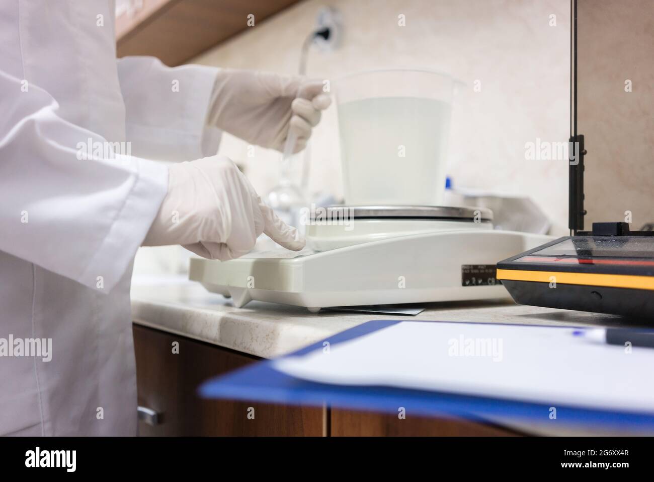 Vista laterale primo piano delle mani di un esperto di sostanze chimiche, analizzando campioni liquidi con attrezzature moderne nel laboratorio di una cosmetica fa Foto Stock