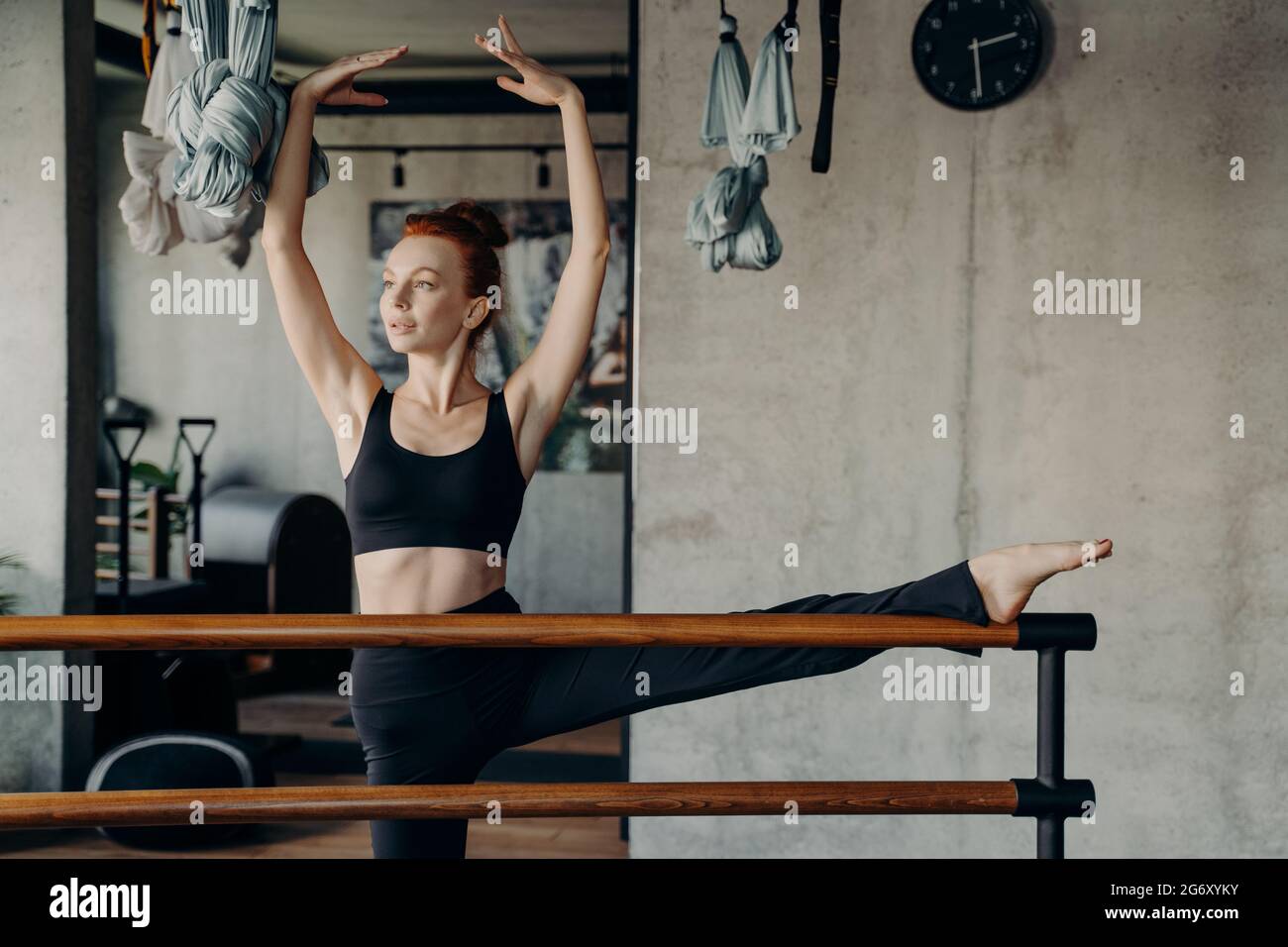 Giovane donna in forma con le mani sopra la testa in posizione classica braccio balletto mentre si fa esercizi di stretching Foto Stock