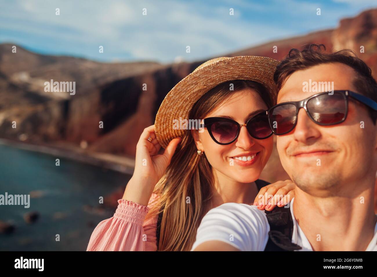 La coppia amorevole prende selfie godendo la luna di miele sulla spiaggia rossa sull'isola di Santorini, Grecia. Vacanze estive. In viaggio Foto Stock