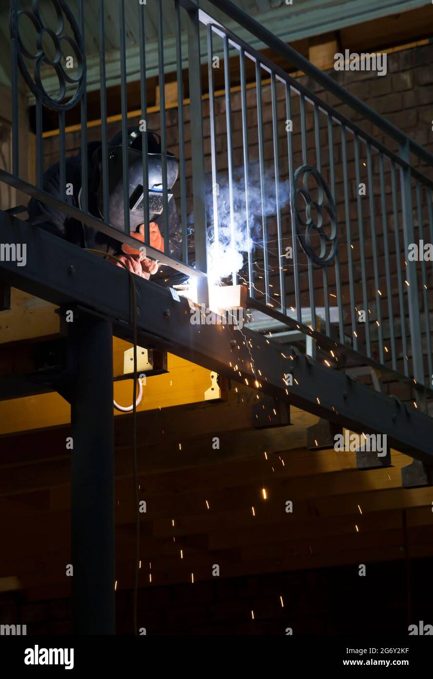 Uomo al lavoro che salda una balastrata. Foto Stock