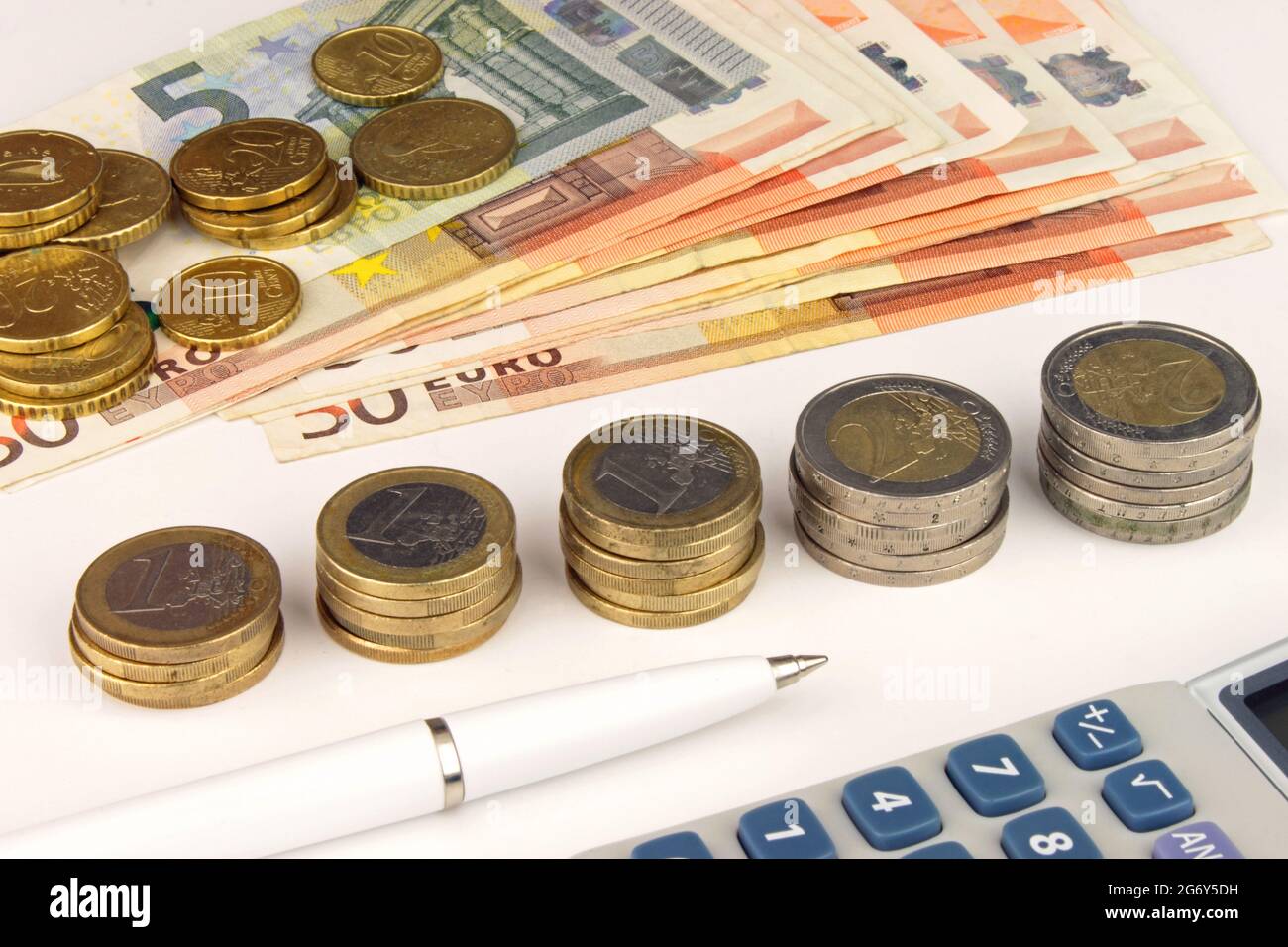 Banconote e monete in euro con calcolatrice e penna, per simboleggiare la finanza europea. Foto Stock