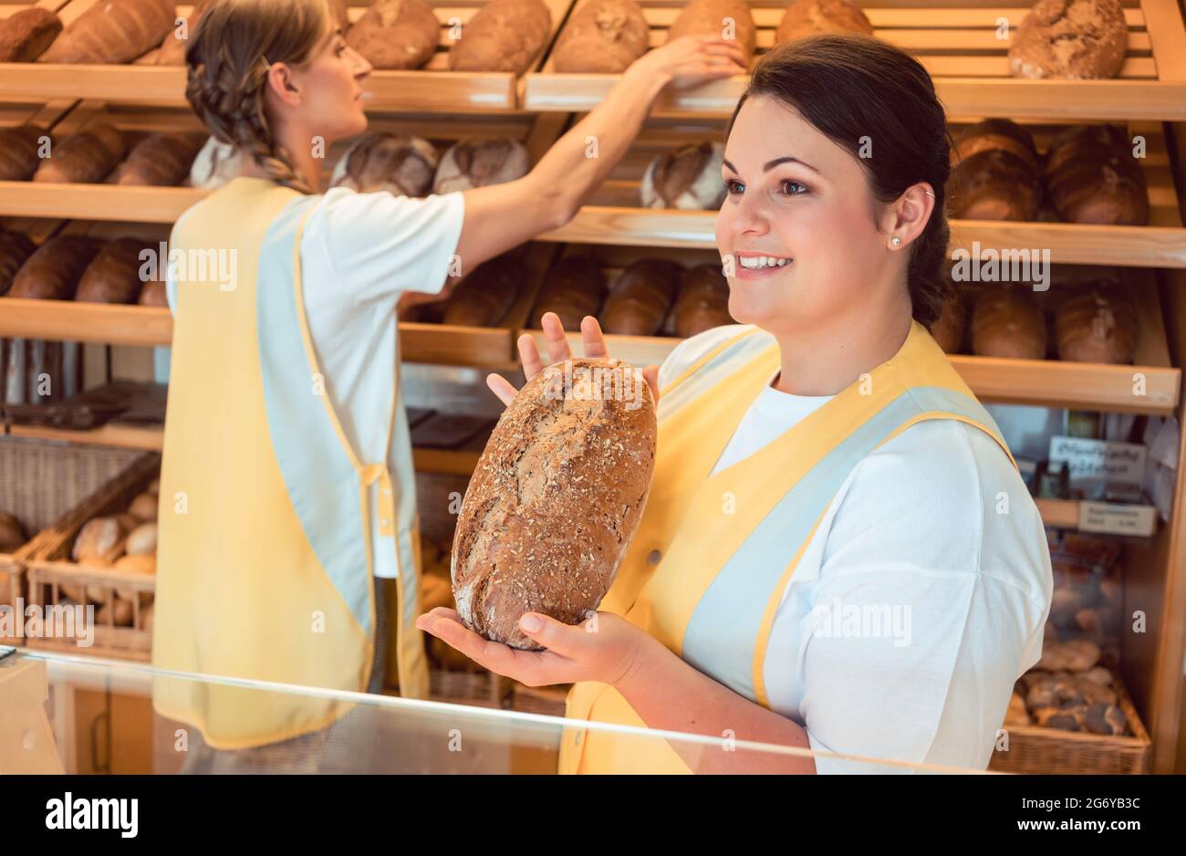 Due salesladies vendita di pane ed altri prodotti di panificio a lavorare come un team Foto Stock