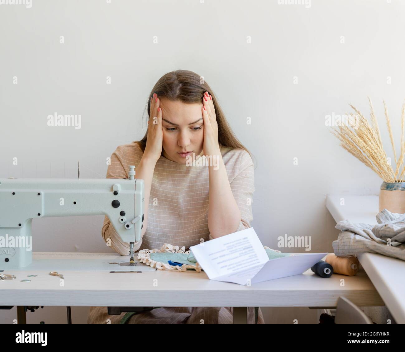 Frustrato buisnesswoman che ha problemi con il pagamento di ipoteca mentre sedendosi al suo proprio atelier di moda Foto Stock