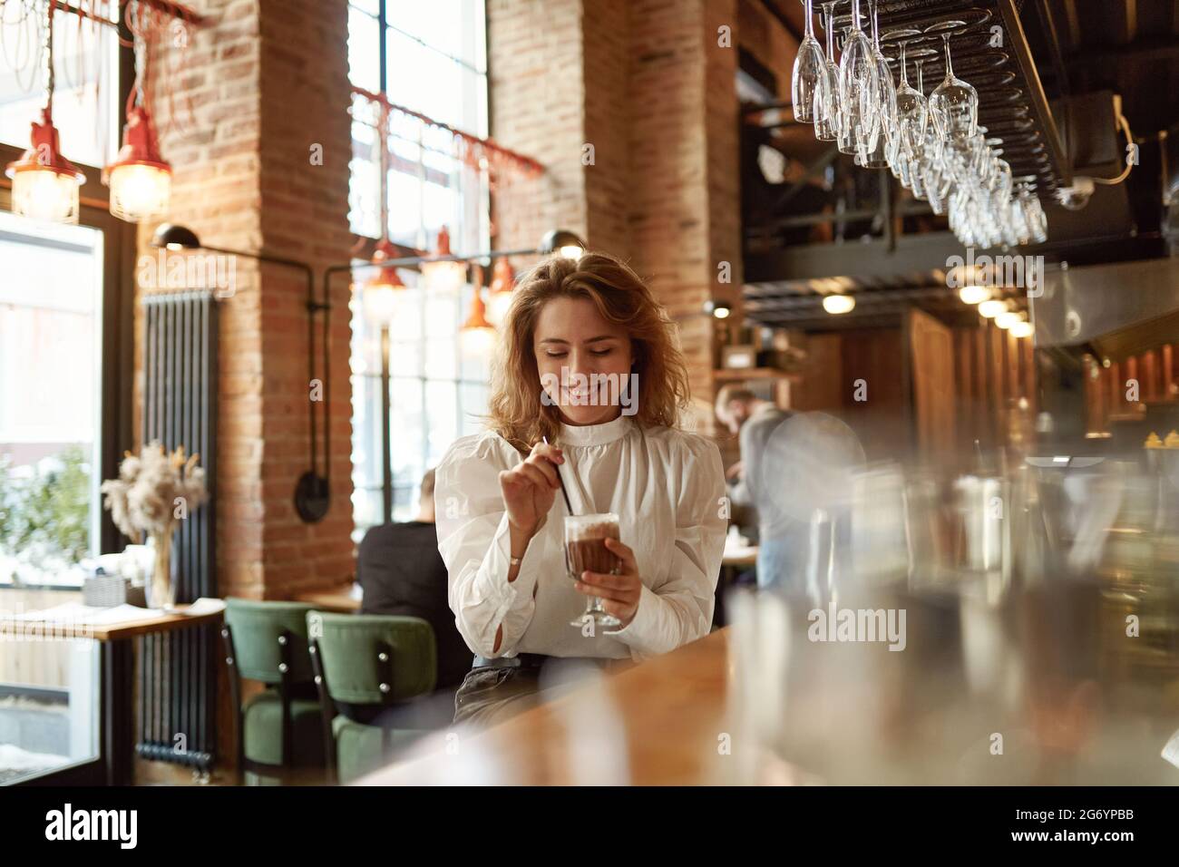 Donna che ama il caffè caldo mentre si siede al bancone del bar Foto Stock Donna che ama il caffè caldo mentre si siede al bancone del bar Foto Stock