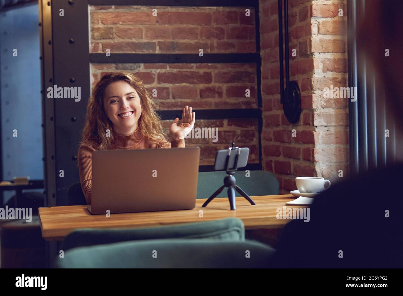 Donna sorridente e sventolante registrazione vlog su smartphone Foto Stock