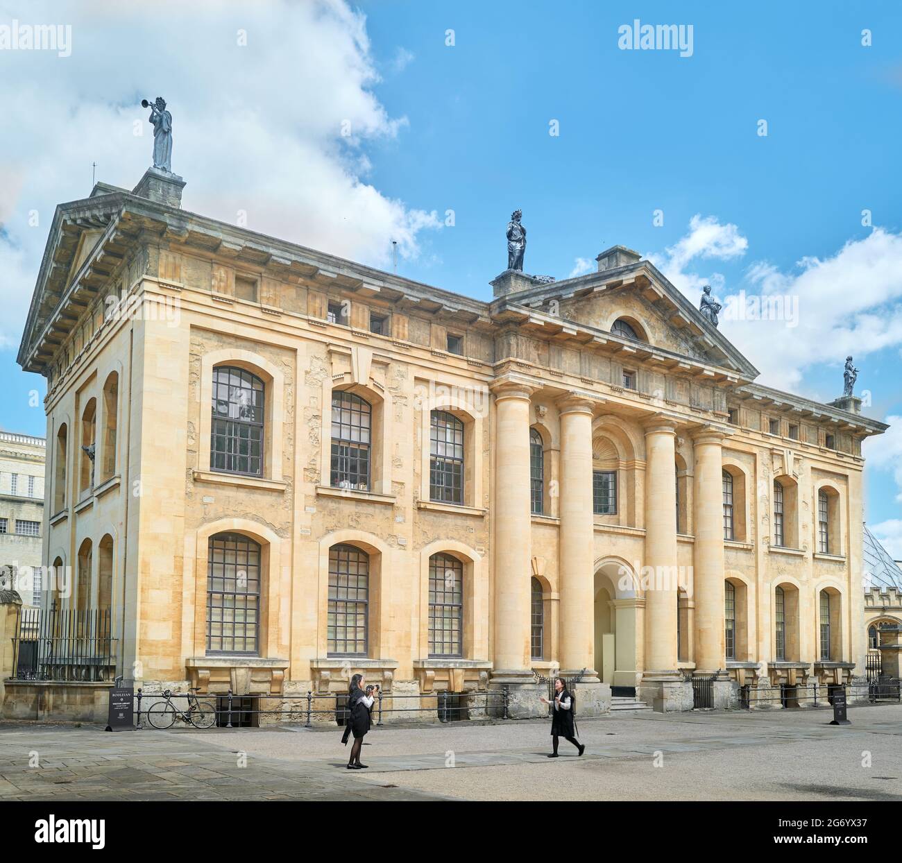 Due studentesse prendono e posano per scattare fotografie all'esterno dell'edificio Clarendon, l'università di Oxford, Inghilterra. Foto Stock