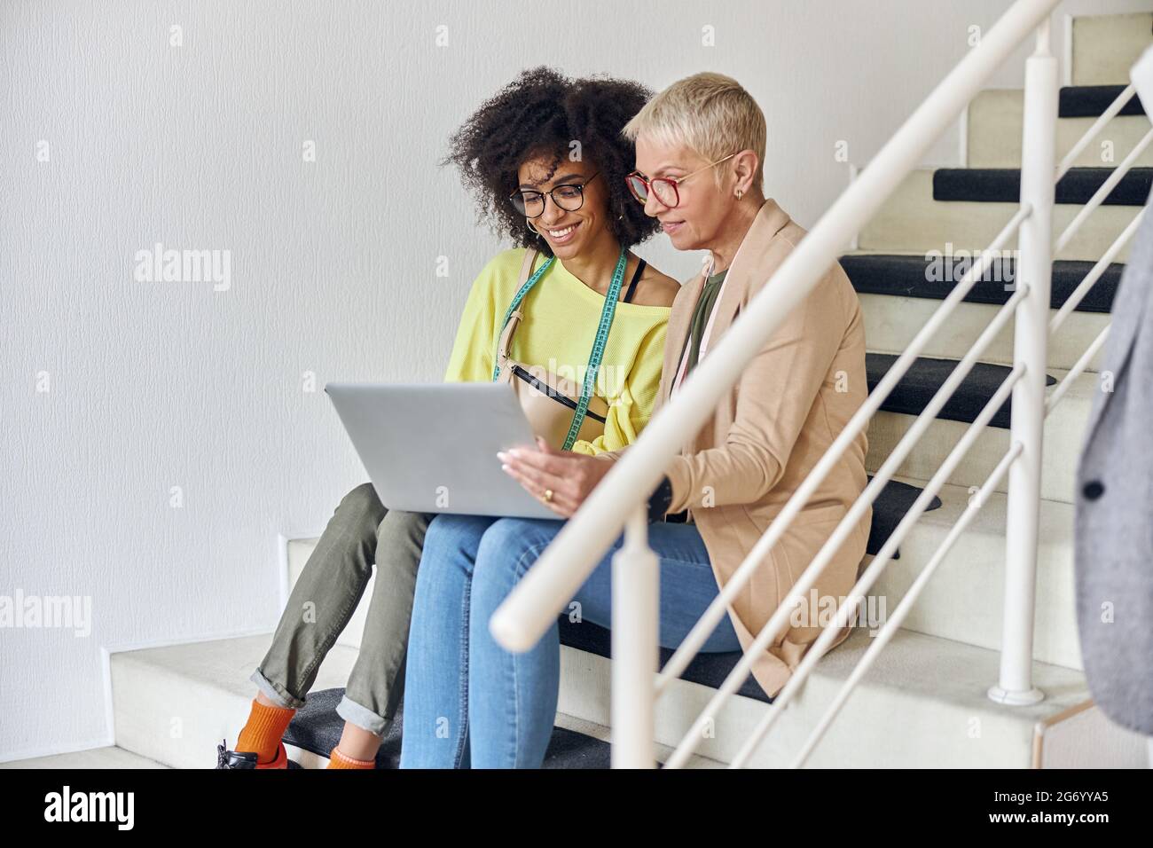 Donna matura e giovane afroamericano usano le cuciture per computer portatile su scala in studio di design Foto Stock