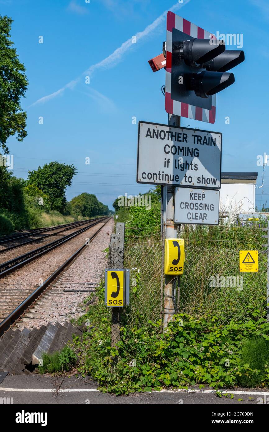 luci lampeggianti e segnali di avvertimento a livello ferroviario che attraversano la regione meridionale del sussex occidentale Foto Stock