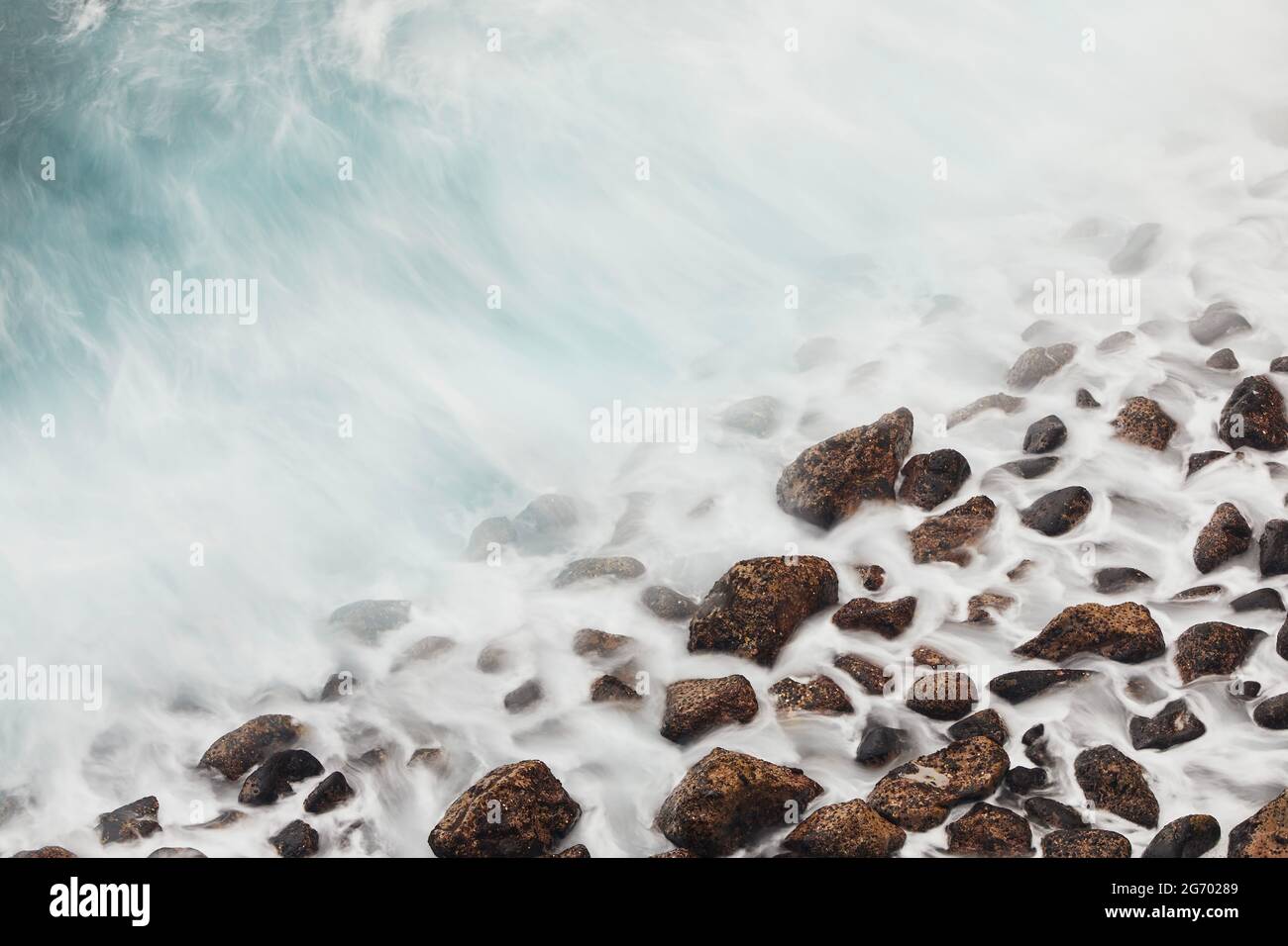 Vista ad alto angolo sulla spiaggia in pietra. Il mare ondeggia in movimento. Tenerife, Isole Canarie, Spagna. Foto Stock