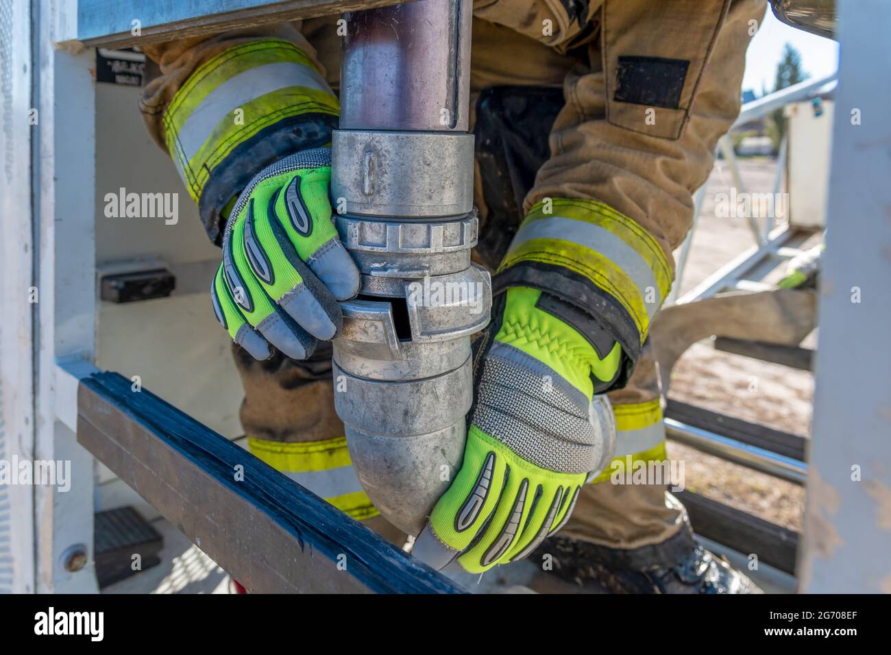Immagine verticale di un pompiere che unisce le tubazioni flessibili per spegnere gli incendi Foto Stock