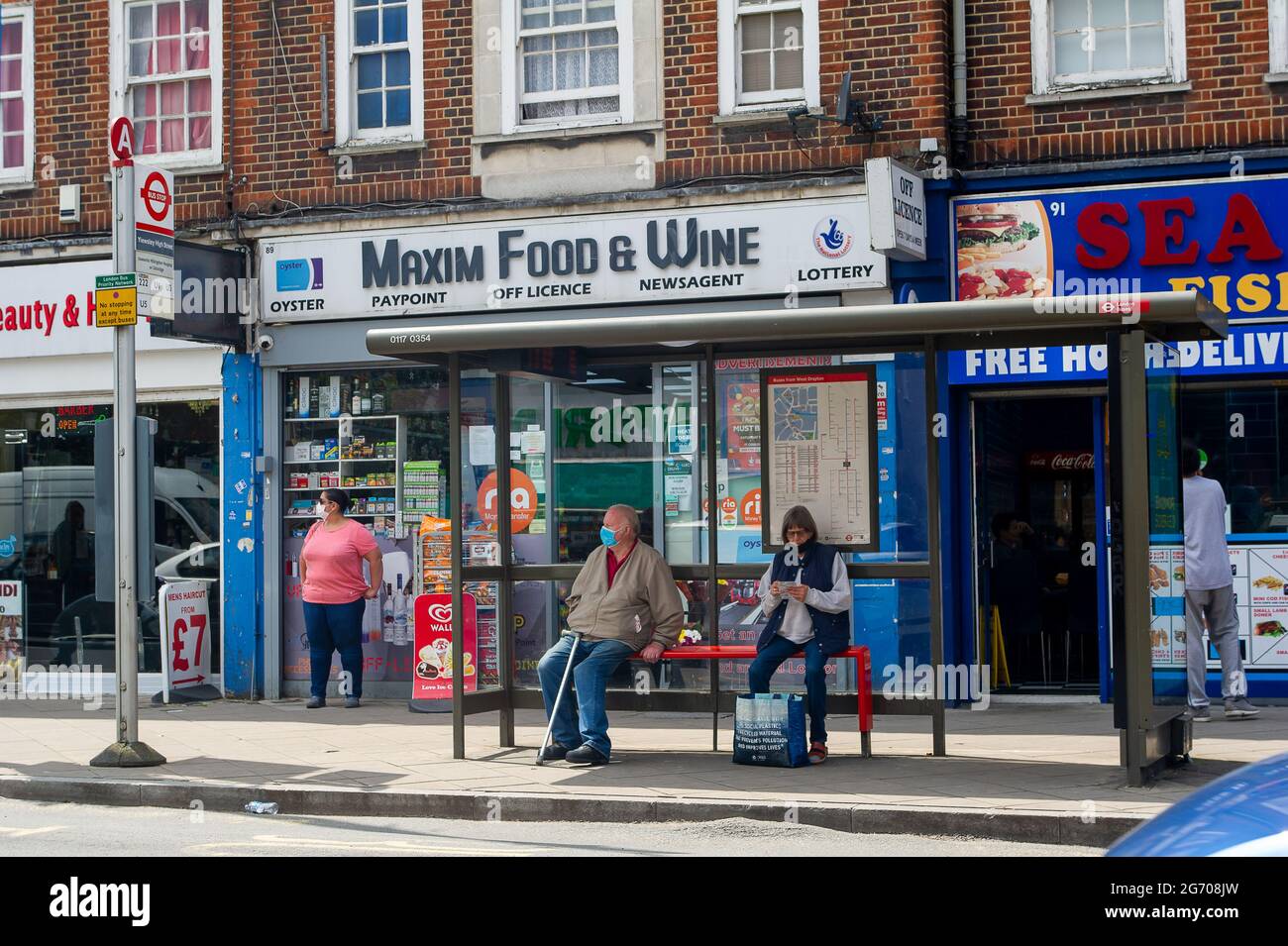 West Drayton, London Borough of Hillingdon, Regno Unito. 9 luglio 2021. Le persone che indossano maschere facciali aspettano ad una fermata dell'autobus. Boris Johnson si aspetta di sollevare il requisito legale dell'uso di maschere facciali sui trasporti pubblici dal 19 luglio 2021, ma questo sta causando preoccupazione tra i viaggiatori, molti dei quali intendono continuare a indossare le loro maschere facciali come il numero di casi Covid-19 aumenta significativamente. Credito: Maureen McLean/Alamy Foto Stock