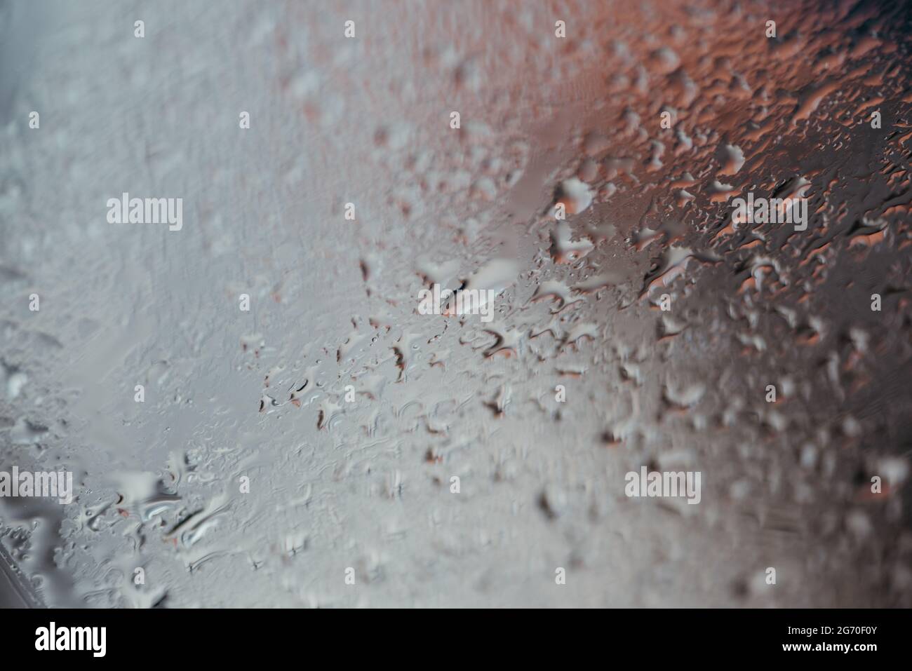 Texture sfondo di gocce d'acqua su un vetro o una finestra con luce rossa in alto a destra. Foto Stock