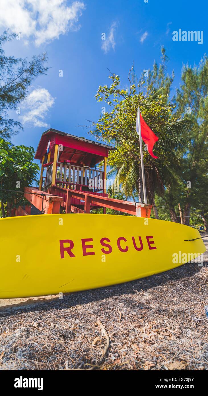 Torre Lifeguard rossa e bordo di salvataggio giallo con bandiera di avvertimento rossa Foto Stock