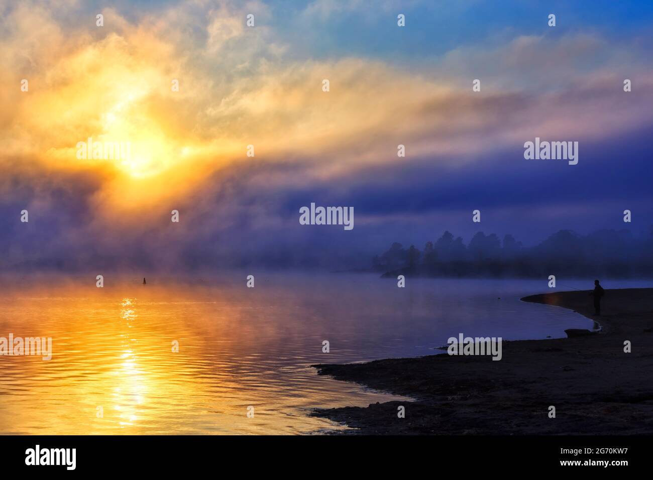 Colorata alba mattutina fredda sul lago Jindabyne, fiume Snowy nelle Snowy Mountains d'Australia con Lonely fisher. Foto Stock