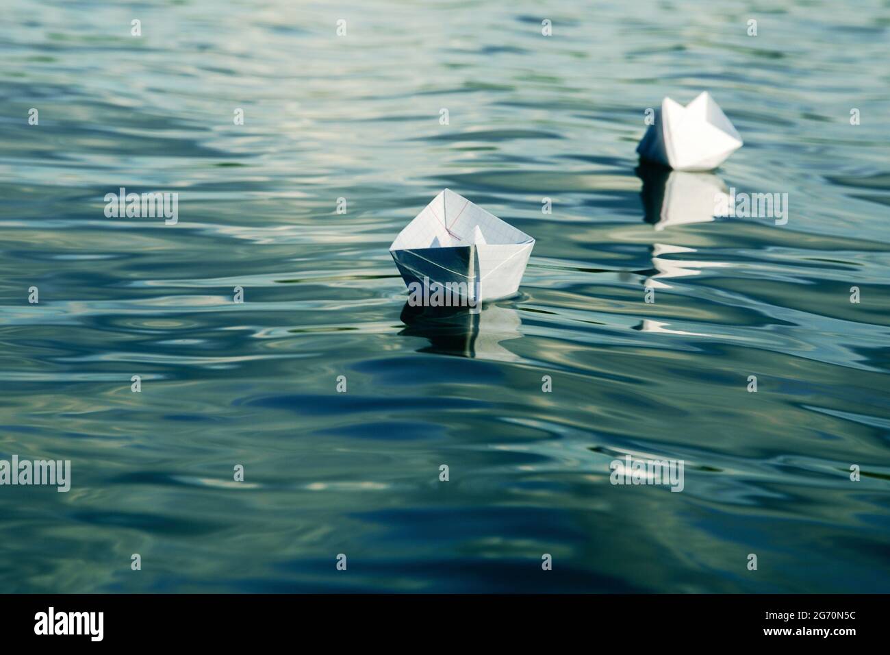barche di carta fatte di un foglio di taccuino della scuola che galleggia in acqua Foto Stock