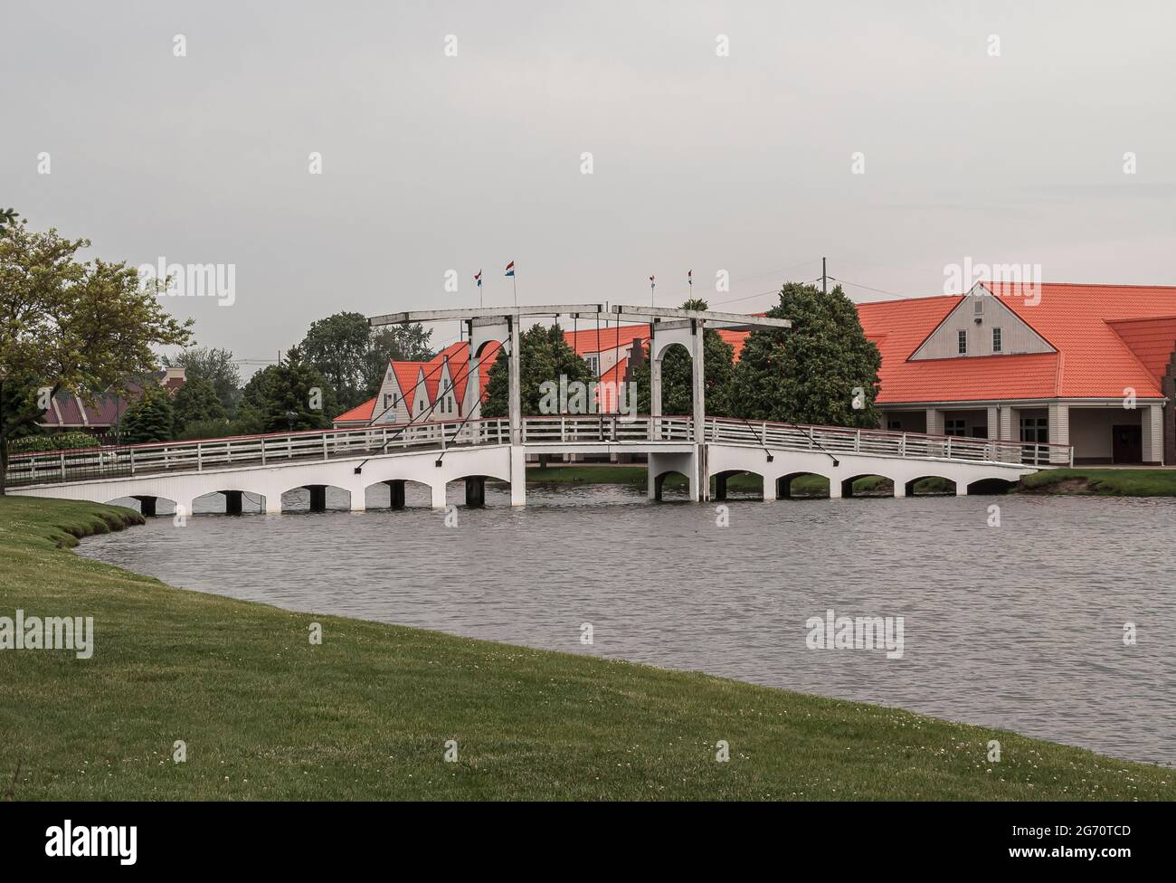 Olanda, MI, USA - 8 giugno 2008: Nelis Dutch Village. Paesaggio con tipico ponte storico pull-up sopra l'acqua di stagno sotto il cielo grigio. Tetto rosso mod Foto Stock