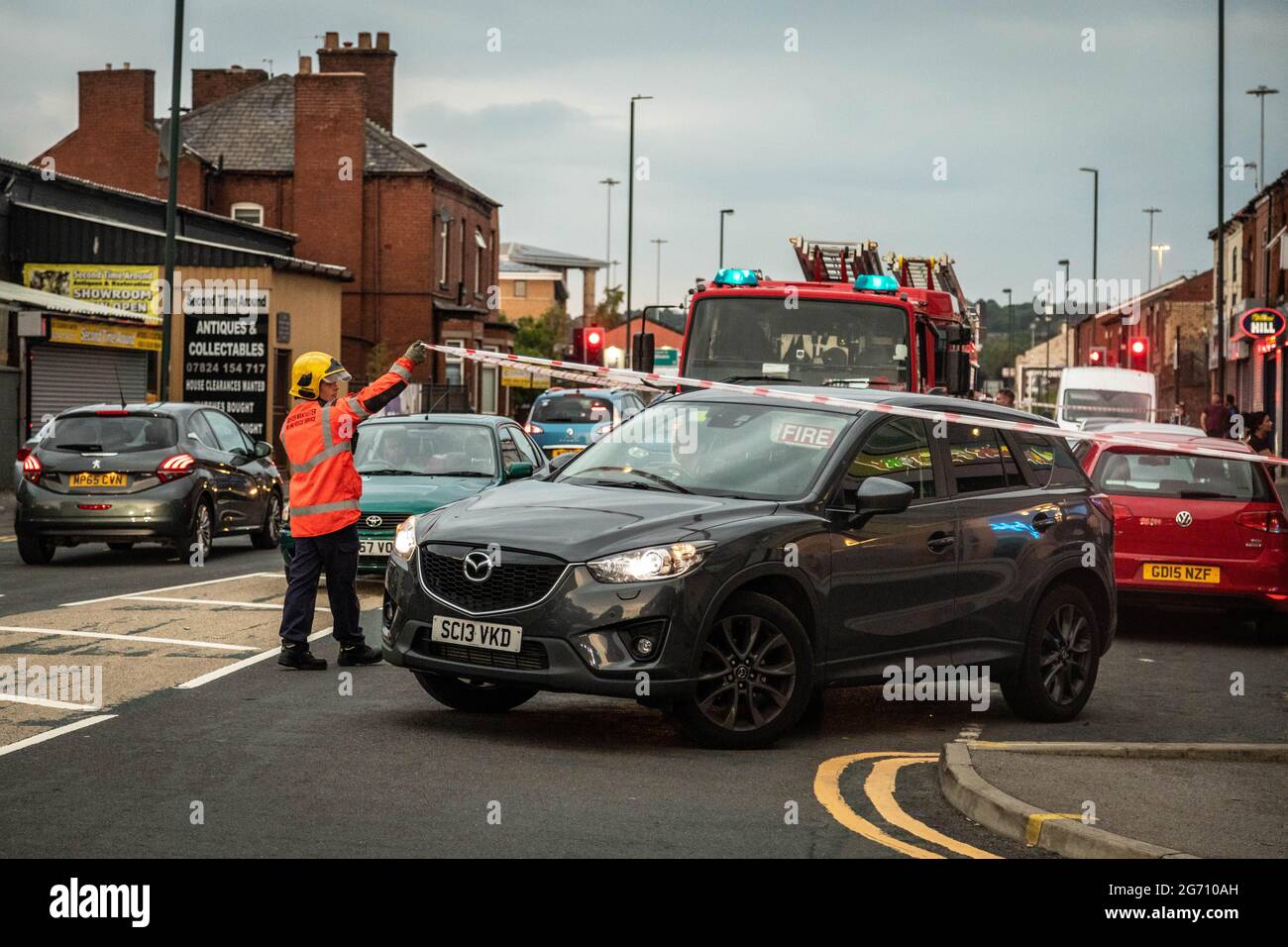 Manchester, Regno Unito. 09 luglio 2021. Un uomo solleva il nastro mentre il comandante del fuoco lascia la scena del fuoco della casa a Manchester.Greater Manchester Fire Service Block off Norman Street, Failsworth dopo un incendio in una casa in un appartamento su Manchester Road. I residenti dicono che il fuoco della casa è stato causato da un uomo che ha voluto commettere suicidio, tuttavia rapporti contrastanti anche mi è venuto che l'uomo stava cucinando. Due camion dei vigili del fuoco e un comandante dei vigili del fuoco hanno risposto alla scena. (Foto di Ryan Jenkinson/SOPA Images/Sipa USA) Credit: Sipa USA/Alamy Live News Foto Stock