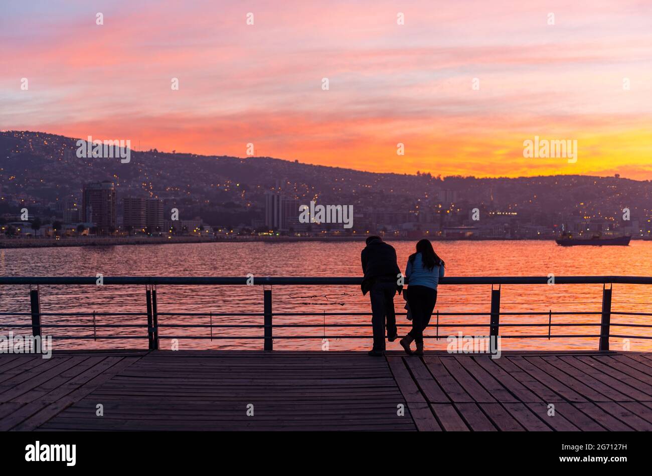 Lo skyline di Valpraraiso e la baia sull'Oceano Pacifico con una romantica coppia in primo piano godendo la vista al tramonto, Cile. Foto Stock