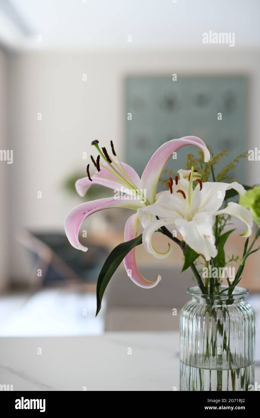 Primo piano di un bouquet di fiori di giglio in un vaso di vetro, all'interno di una casa Foto Stock