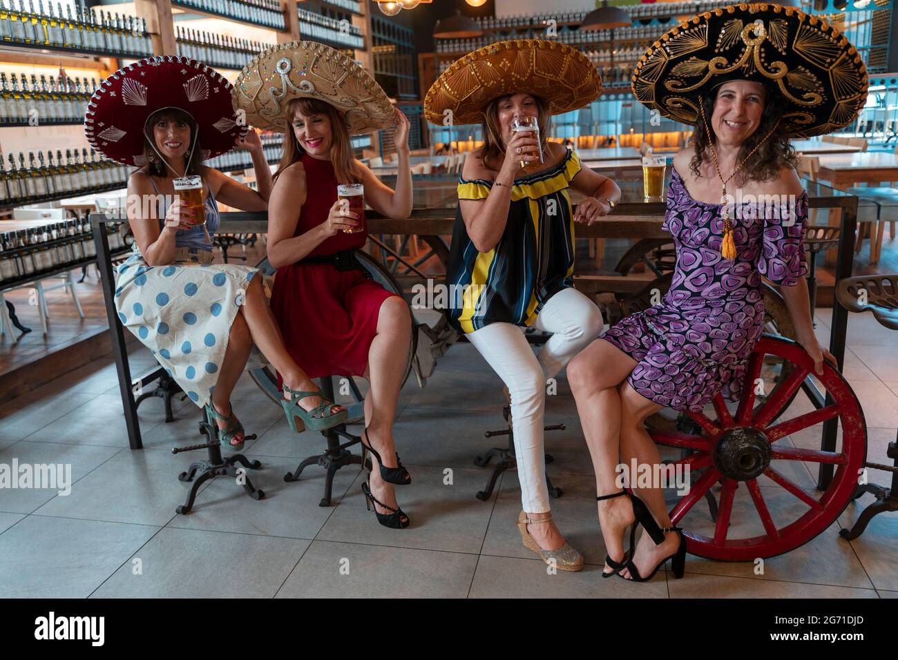 Gruppo di donne mature sta bevendo birra in un pub che indossa sombreros messicani Foto Stock