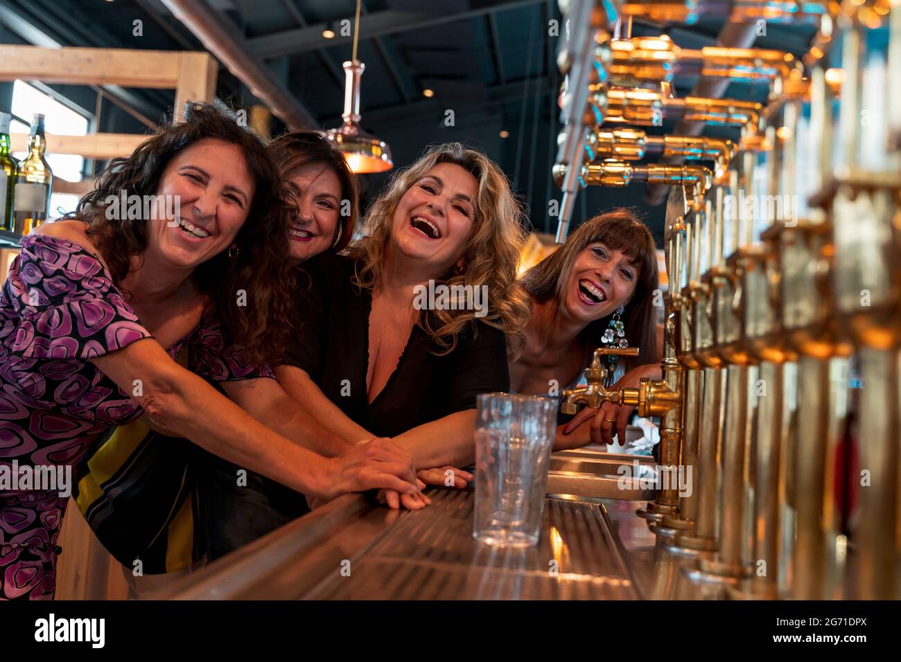 un gruppo di donne mature sorridenti beve birra in un pub di fronte a una presa di birra Foto Stock