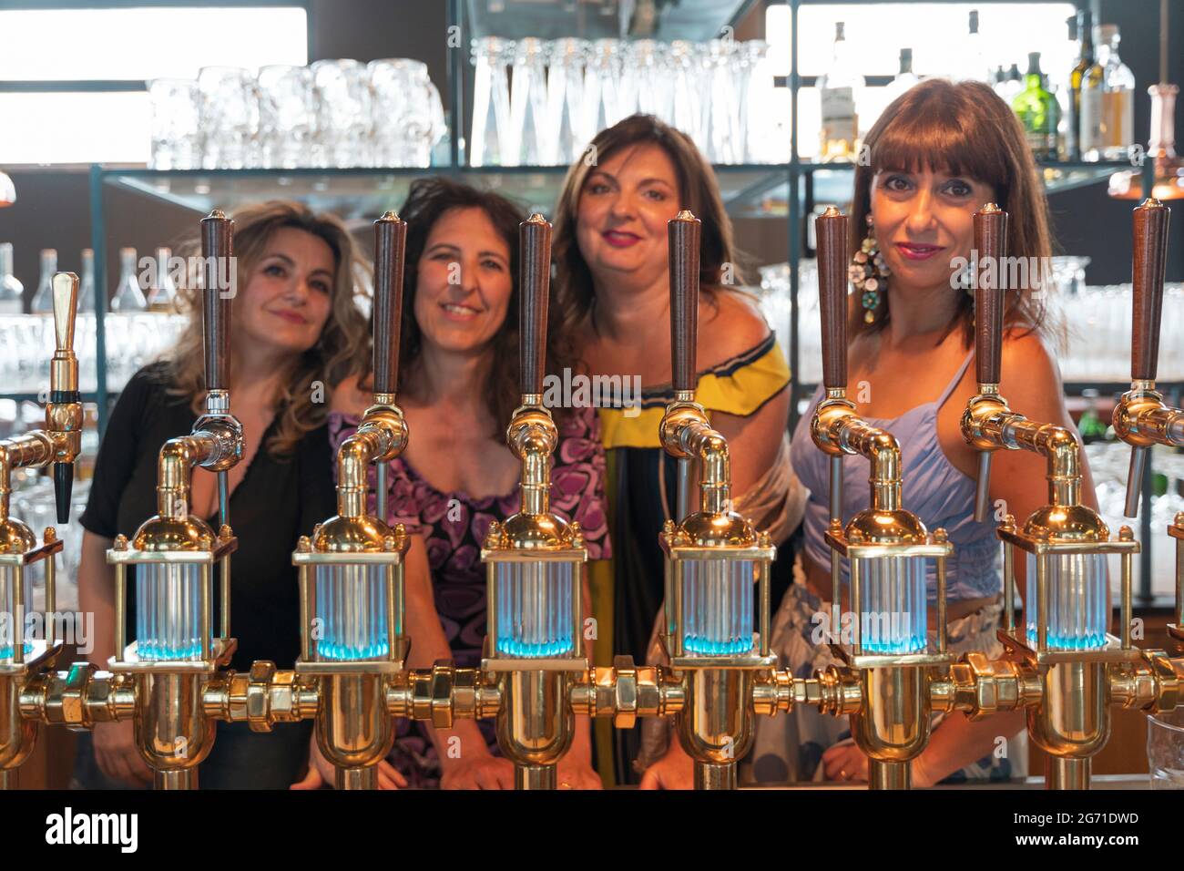 un gruppo di donne mature beve birra in un pub di fronte a una presa di birra. concentratevi sul rubinetto Foto Stock