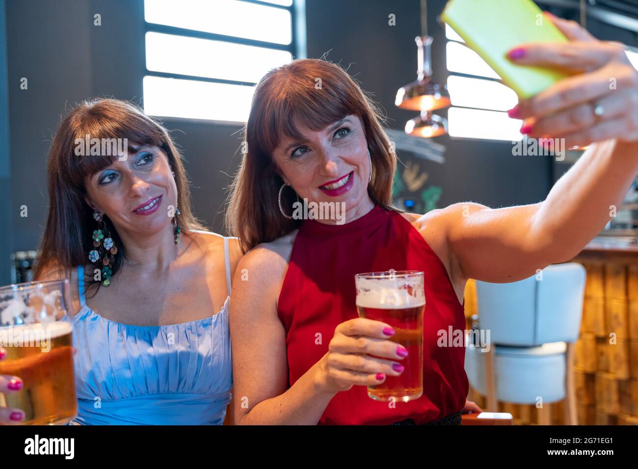due amiche prendono un selfie mentre bevono birra in un pub Foto Stock