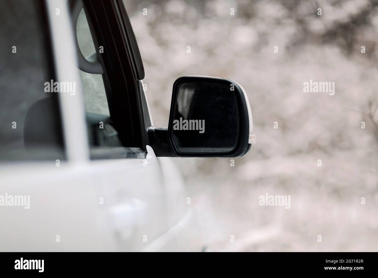 Messa a fuoco morbida del veicolo bianco con specchio ad ala parcheggiato in campagna innevata in inverno Foto Stock