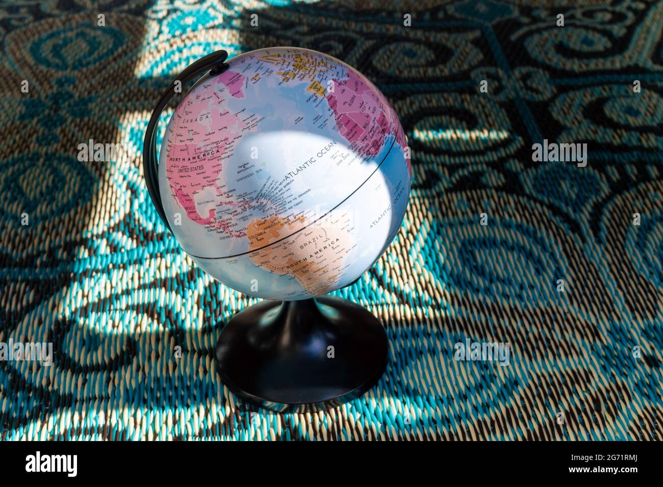 Immagine di un piccolo globo mondiale su un tappeto blu di ispirazione orientale al sole del pomeriggio Foto Stock