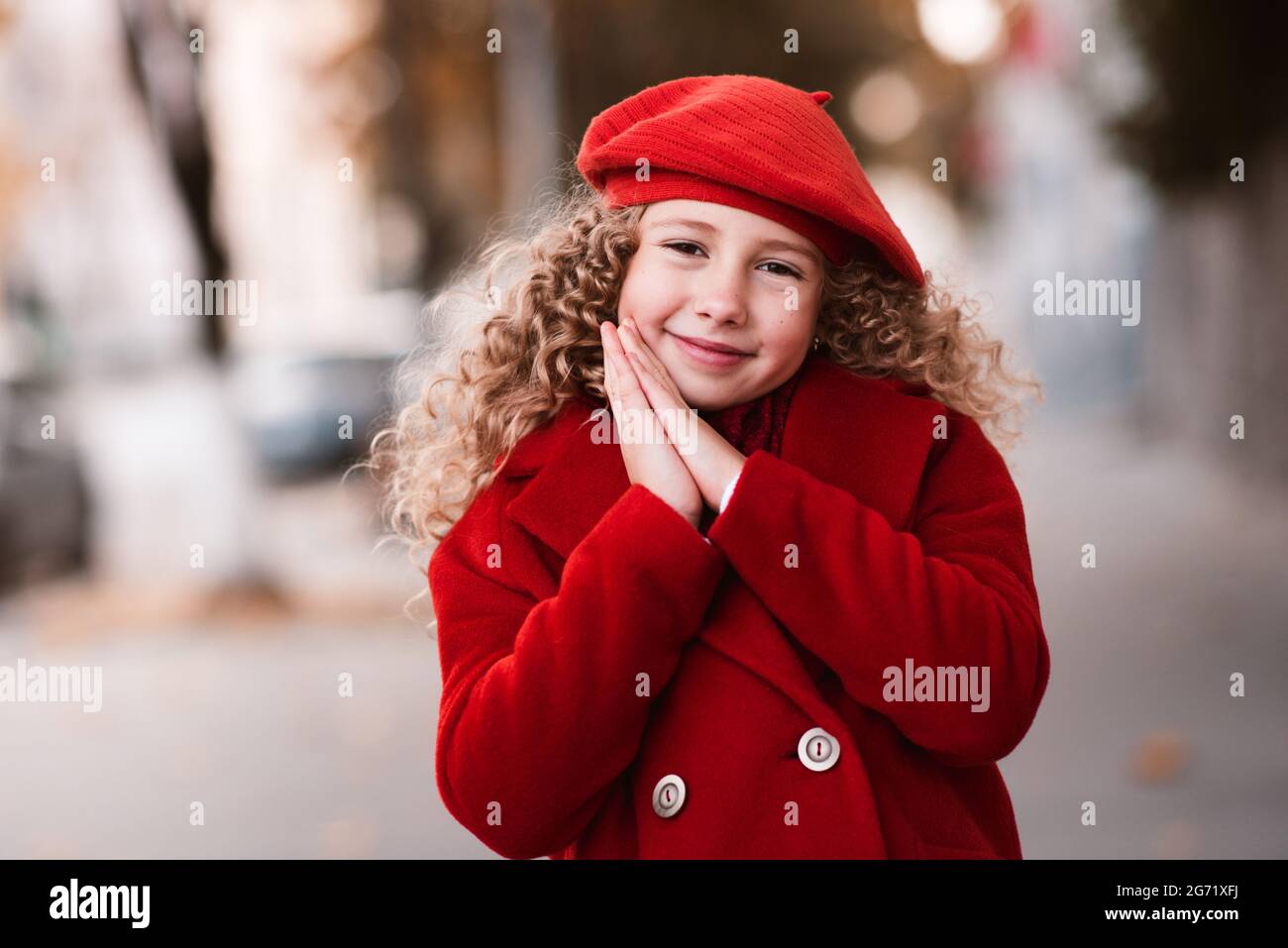 Elegante bambina di 5-6 anni indossa cappello rosso e giacca sulla strada  della città all'aperto. Stagione autunnale. Infanzia. Felicità. Bambino con  capelli ricci biondi Foto stock - Alamy