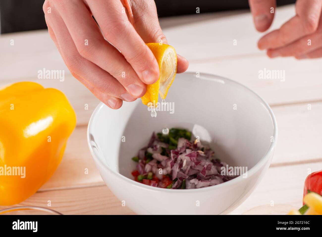 Primo piano sulle mani che spremono il succo da una fetta di limone Foto Stock