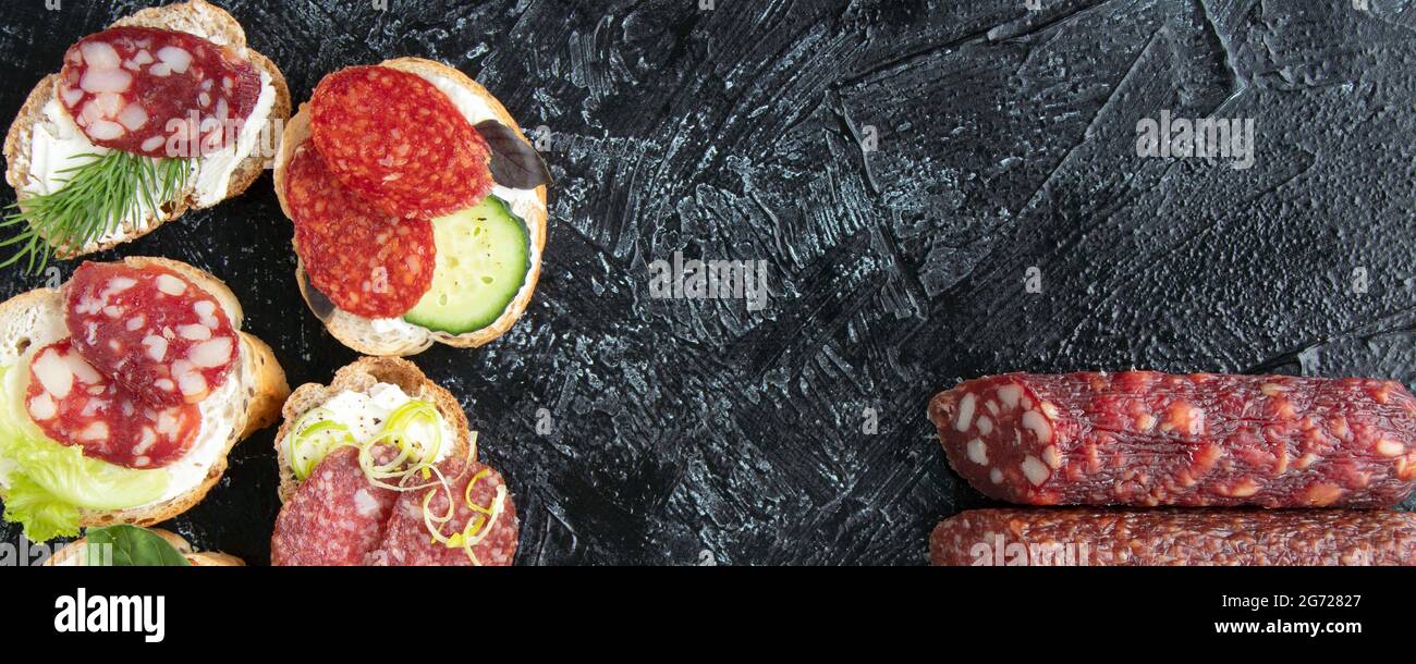 striscione con vista dall'alto su sei panini o spuntini con salsicce e tre tipi di salsicce diverse su sfondo nero con texture e spazio per la copia. fl Foto Stock