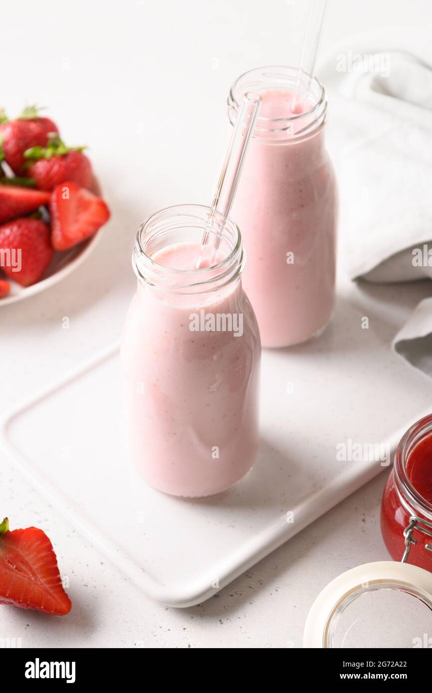 Tradizionale ayurvedico indiano fragola lassi o frullato in due bottiglia su uno sfondo bianco. Formato verticale. Foto Stock