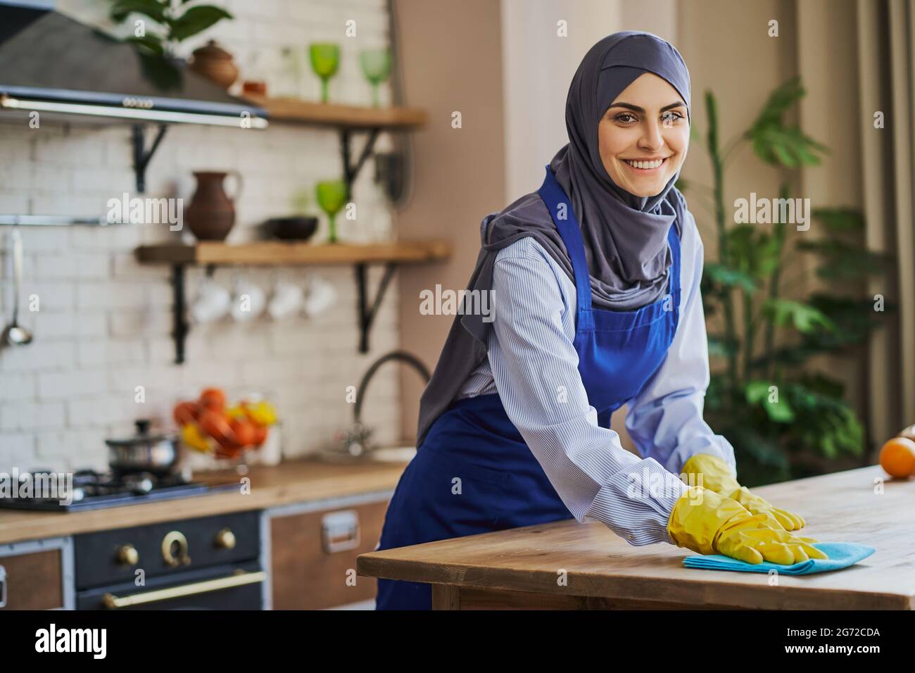 Donna araba che pulisce un tavolo in cucina Foto Stock