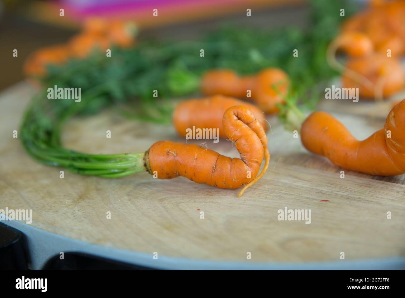 Guarda le carote fresche per bambini dalla forma strana su un tavolo di legno Foto Stock