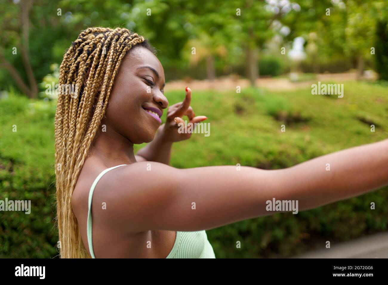 Vista laterale di una donna che fa il segno della vittoria con la mano. Vista ravvicinata di una donna afroamericana con occhi chiusi che prende un selfie facendo segno di pace wi Foto Stock