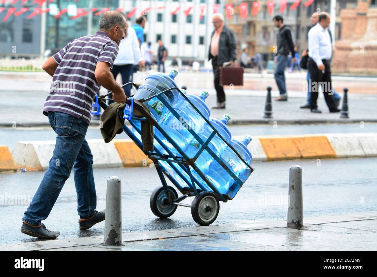 Istanbul, Turchia. L'uomo trasporta acqua per i ristoranti Foto Stock