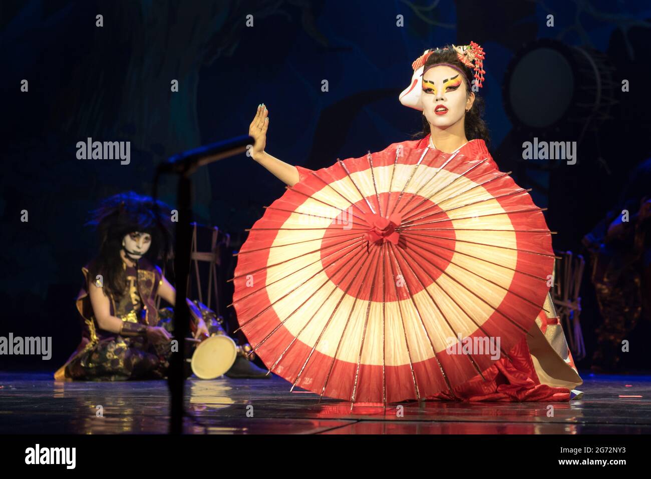 Donna giapponese in kimono tradizionale con ombrello seduto sulle ginocchia nel buio, un altro sul backstage. Kino Kitsune volpe è un personaggio giapponese Foto Stock