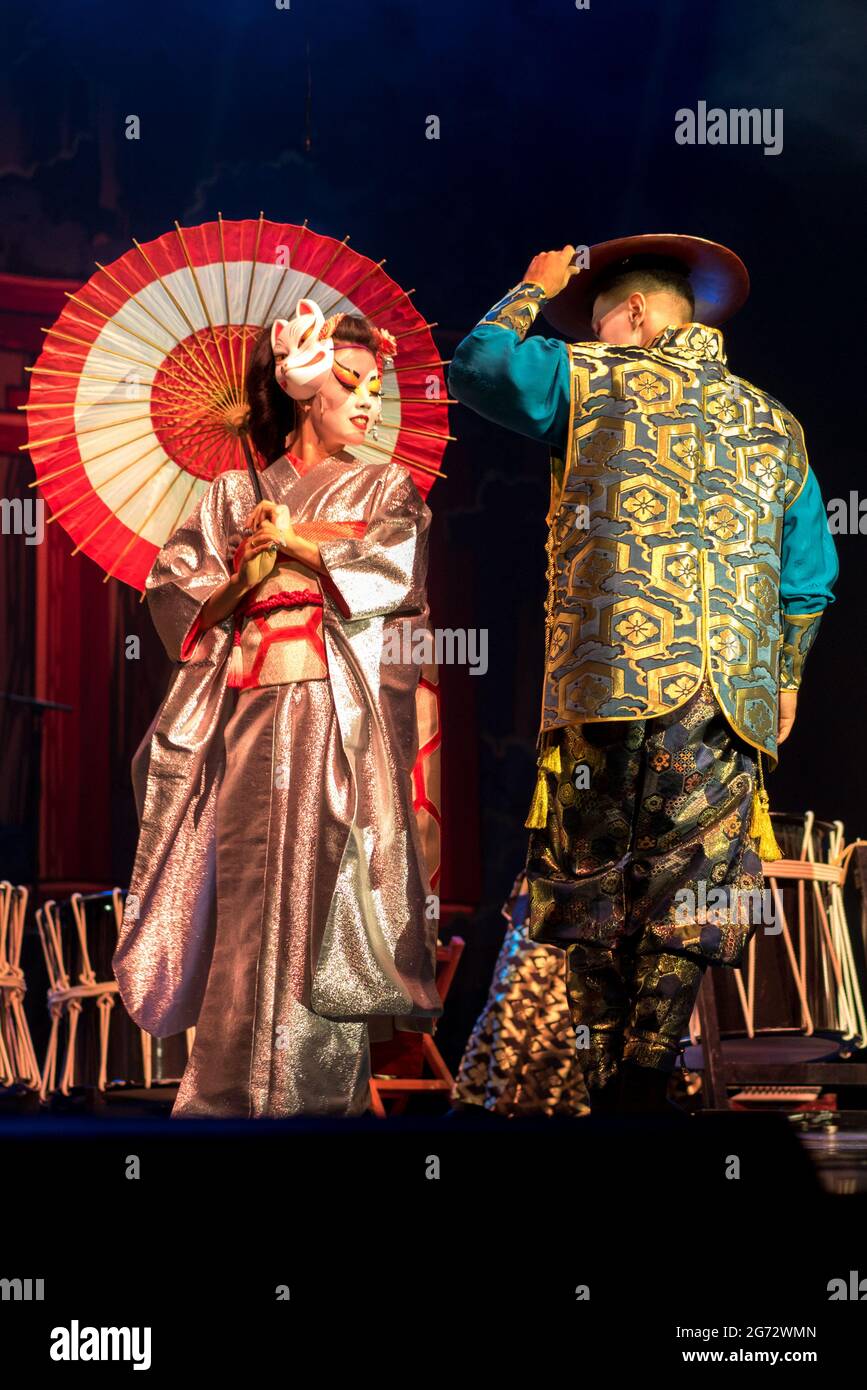 Donna giapponese geisha in kimono tradizionale e incontra e Kino Kitsune fox maschera saluta l'uomo in uno sfondo scuro. Spettacolo tradizionale Giapponese. Foto Stock