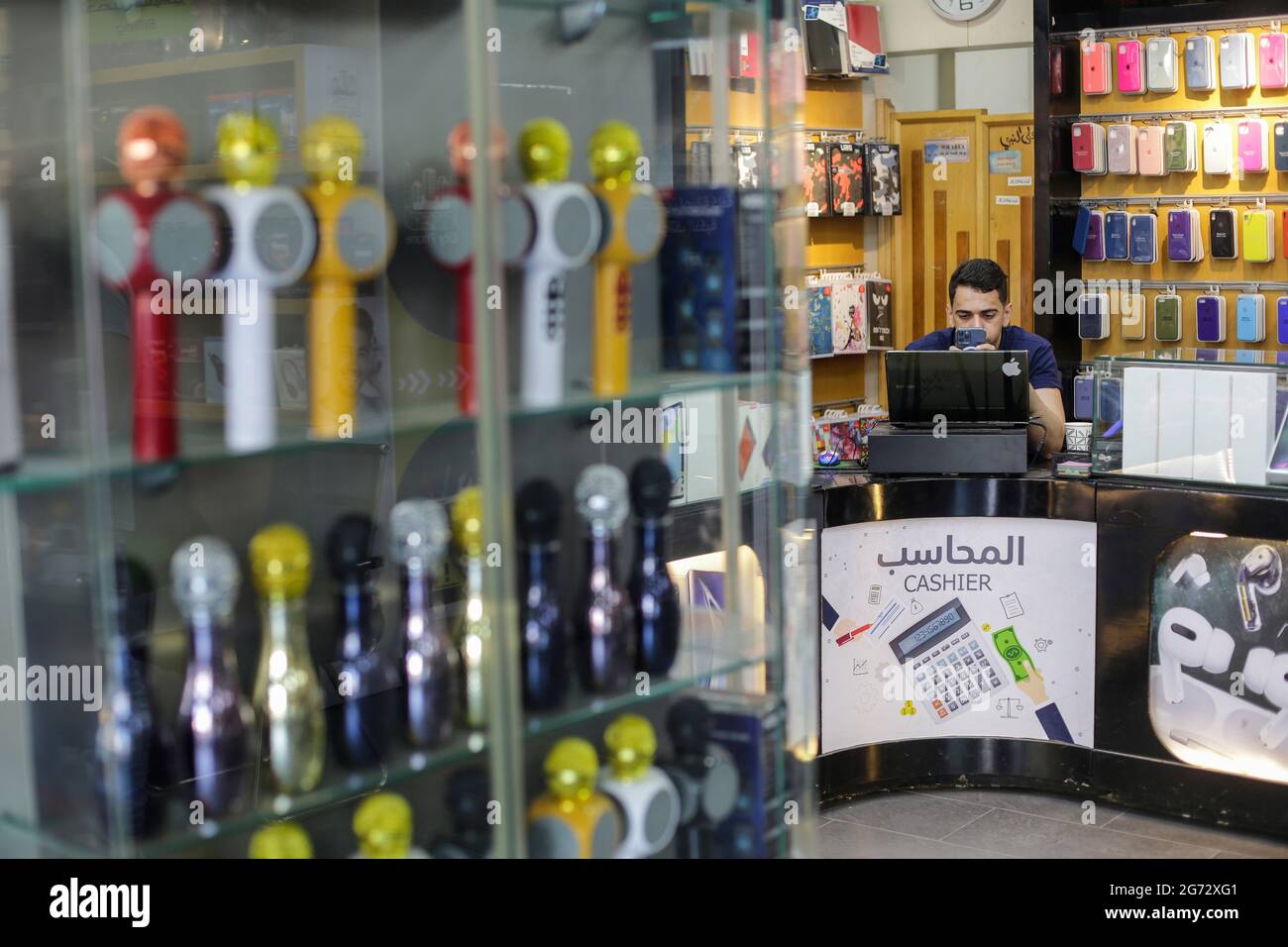 Gaza, Palestina. 10 luglio 2021. Un palestinese lavora in un negozio di telefonia. Con l'aumento dei prezzi, i tassi di disoccupazione e la mancanza di opportunità di lavoro a Gaza, un numero crescente di famiglie sta affrontando la povertà dopo aver perso il lavoro durante l'assedio e la guerra nella striscia di Gaza. Credit: SOPA Images Limited/Alamy Live News Foto Stock Gaza, Palestina. 10 luglio 2021. Un palestinese lavora in un negozio di telefonia. Con l'aumento dei prezzi, i tassi di disoccupazione e la mancanza di opportunità di lavoro a Gaza, un numero crescente di famiglie sta affrontando la povertà dopo aver perso il lavoro durante l'assedio e la guerra nella striscia di Gaza. Credit: SOPA Images Limited/Alamy Live News Foto Stock