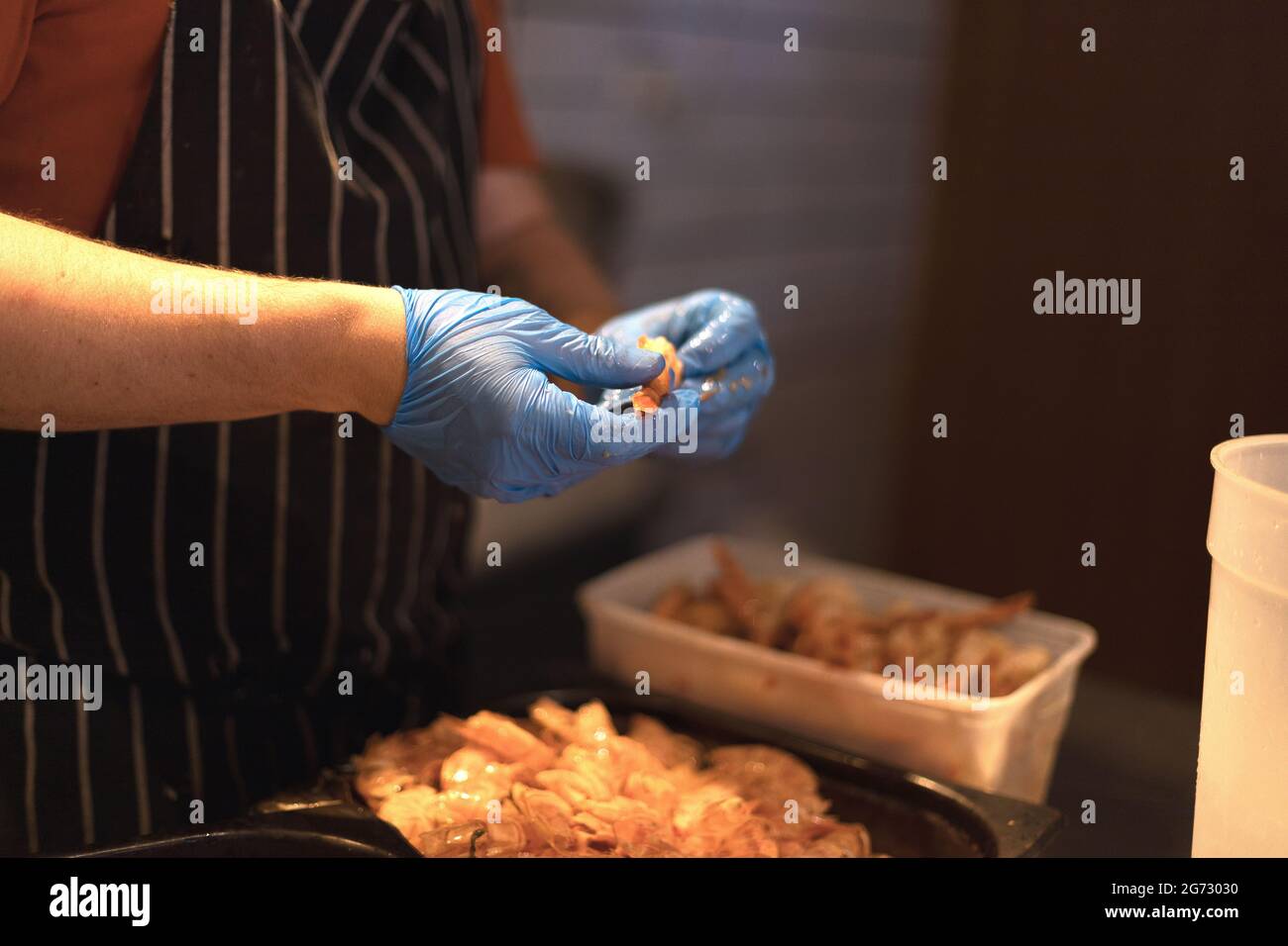 chef peeling gamberi con guanti blu Foto Stock