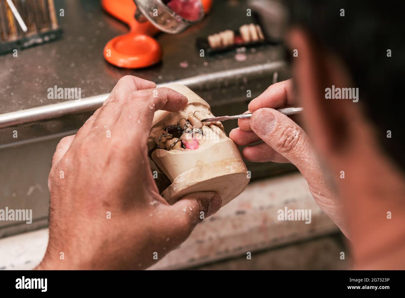 tecnico dentale scavare una protesi dentale con un bisturi Foto Stock