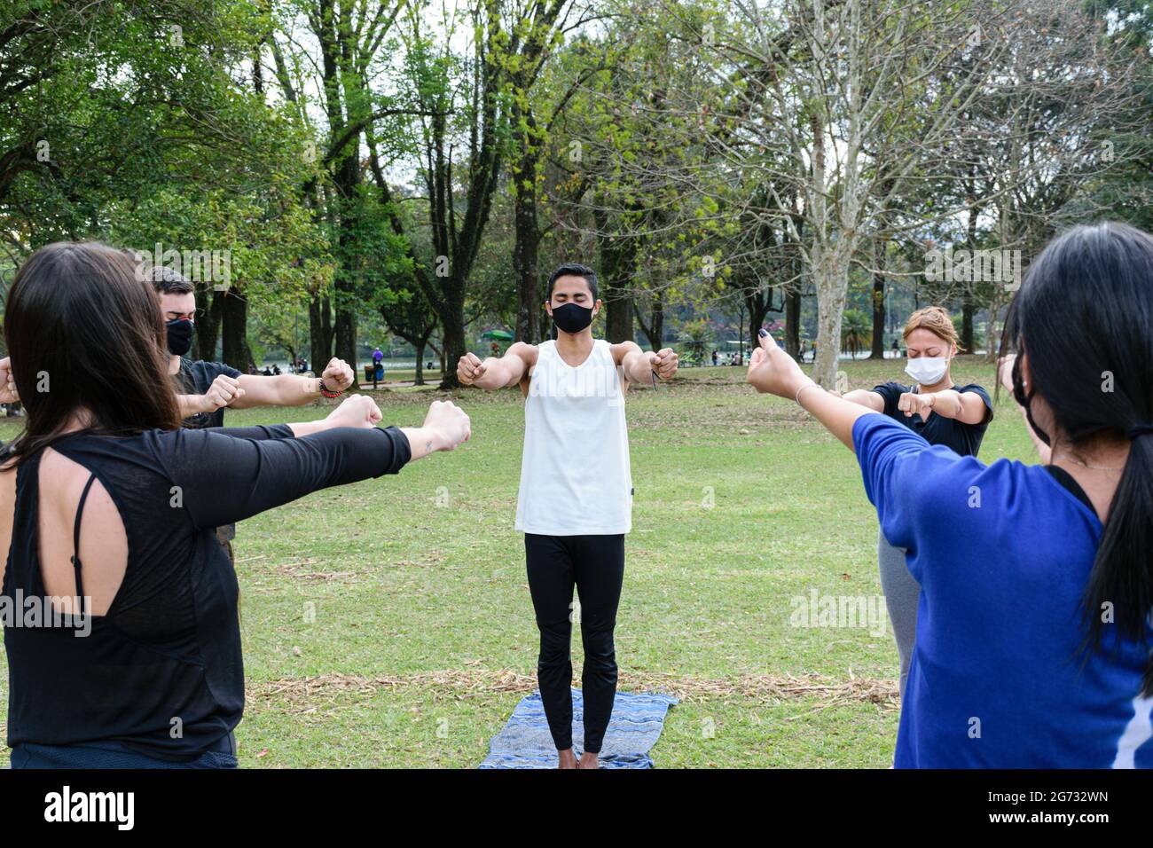 Sao Paulo, Sao Paulo, Brasile - Luglio, 04 2021: Giovane brasiliano di 28 anni che dà lezioni di yoga in una giornata di sole nel parco pubblico Ibirapuera. Foto Stock