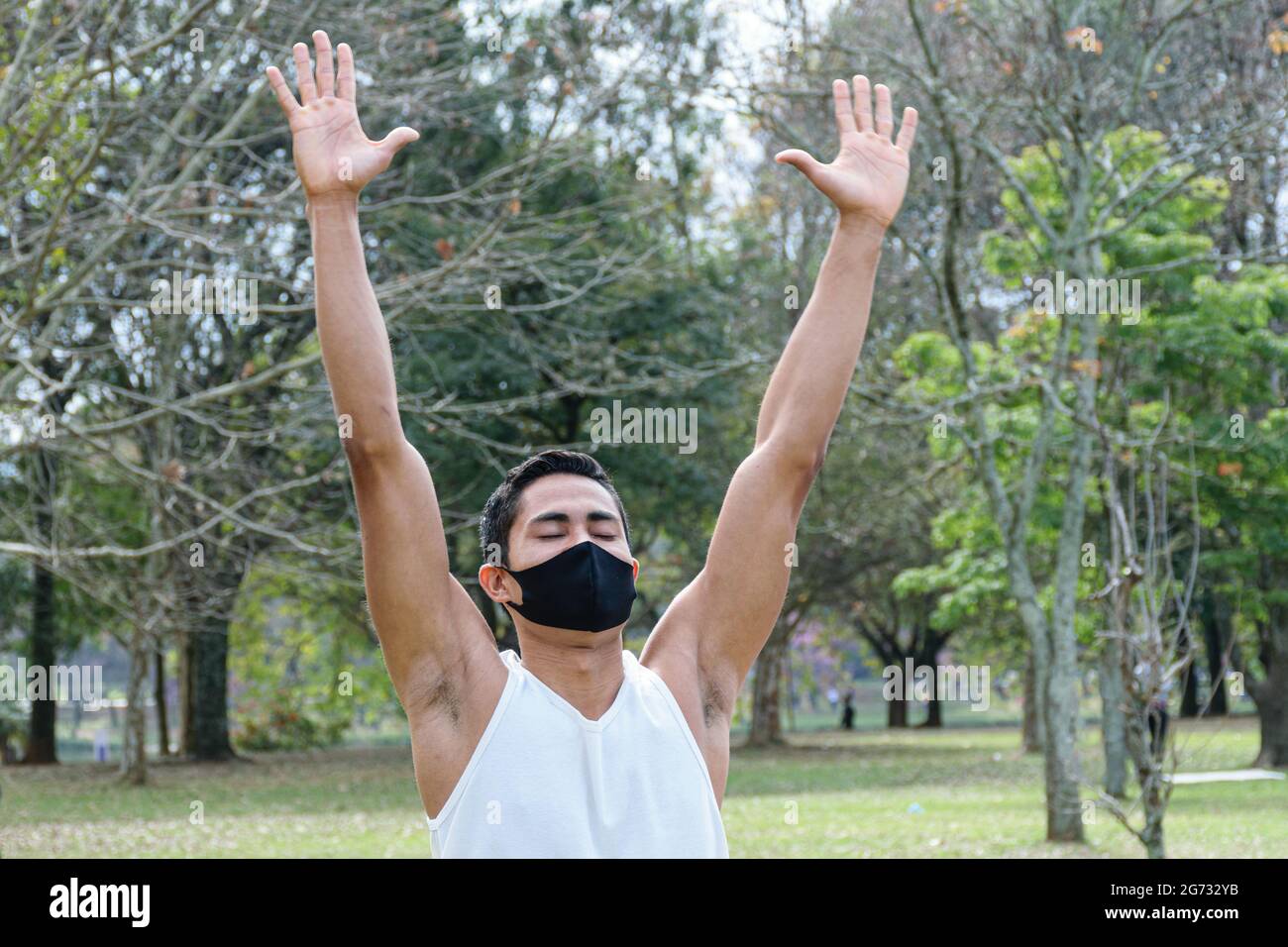 Giovane brasiliano di 28 anni che dà lezioni di yoga all'aperto, salutando con le braccia in su. Foto Stock